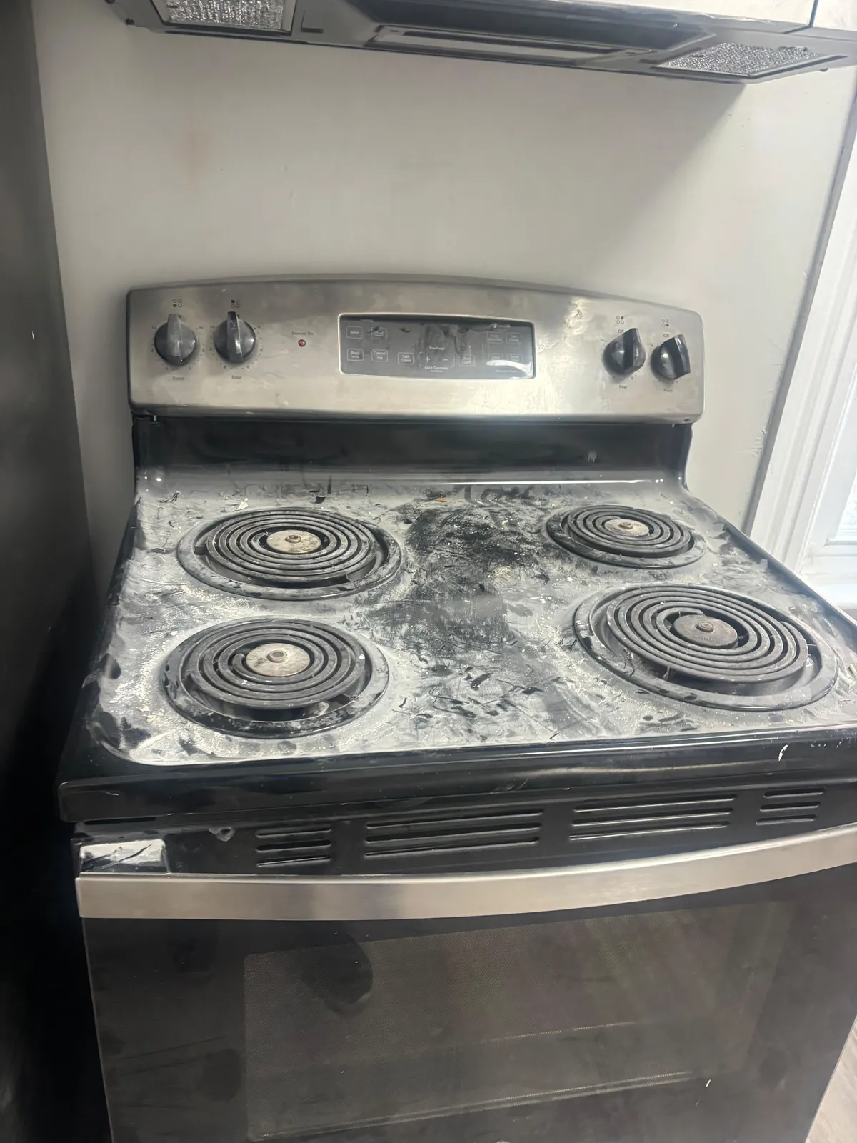 Stovetop with baked-on grime before a deep cleaning